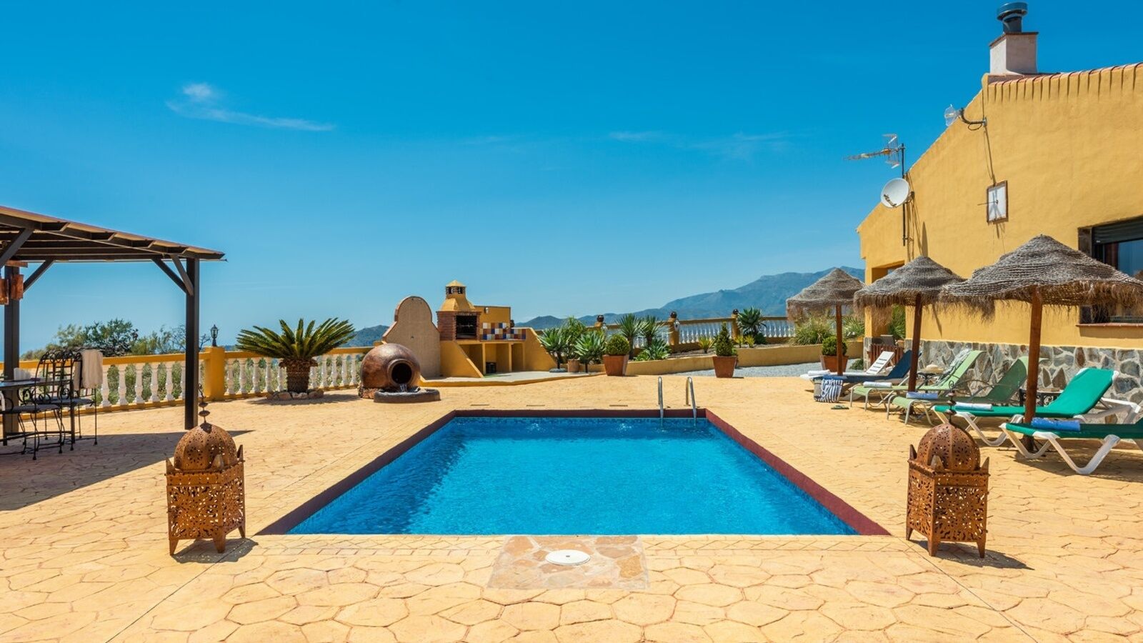 Un área de piscina en la azotea con piscina azul cristalina, sillas de descanso y una pérgola.