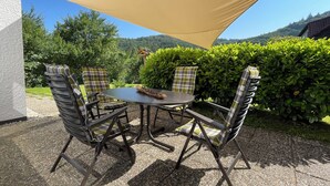 A patio with a table and chairs, a large shade sail, and a view of a green landscape. - Vacation home Buchfink 118sqm near Koblenz & Montabaur (Dies)