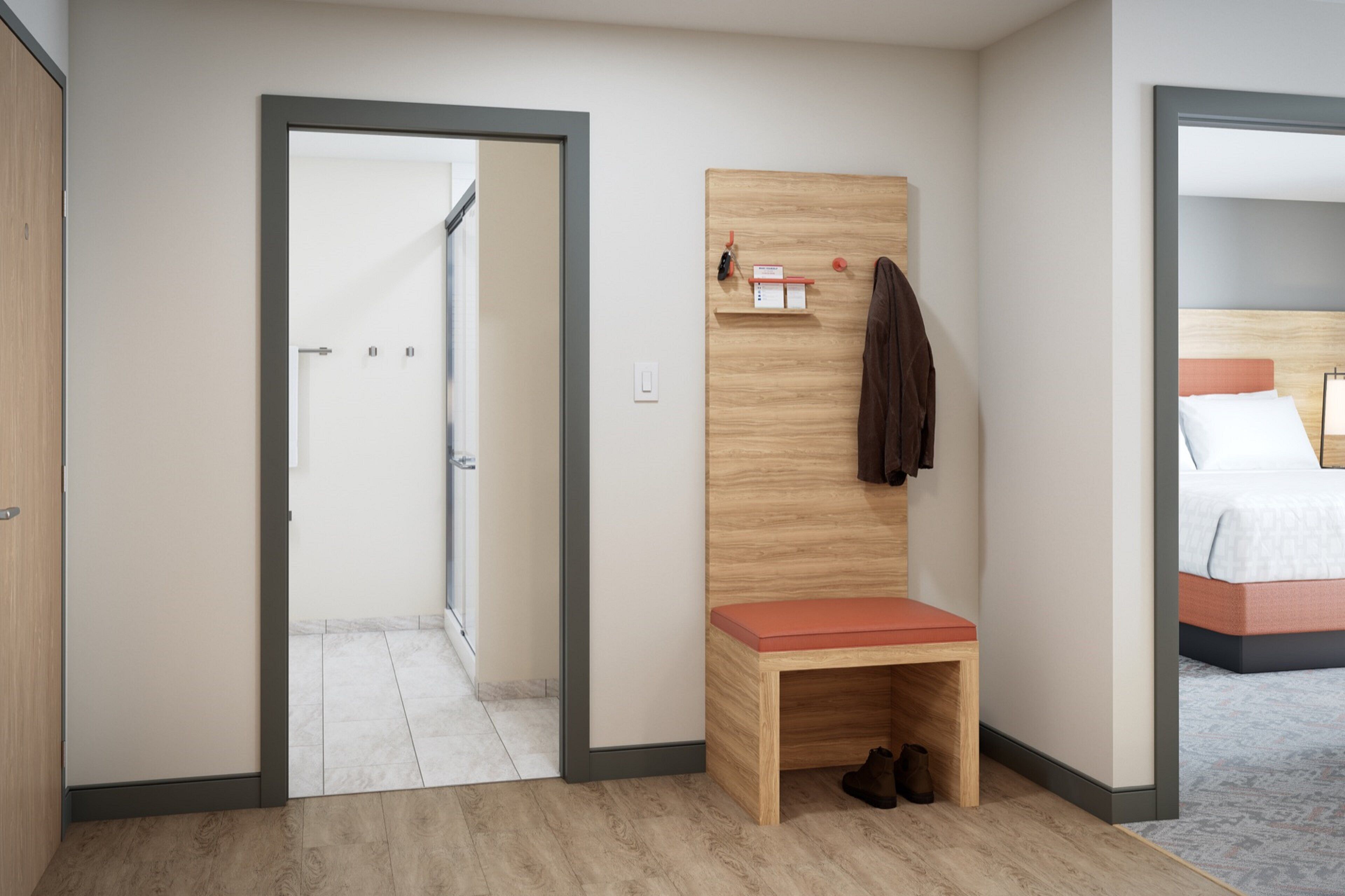 Habitación de hotel con un banco de madera, perchero y cama con cabecera.