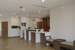 Zona de recepción con un mostrador blanco, piso de madera y señalización de Candlewood Suites.