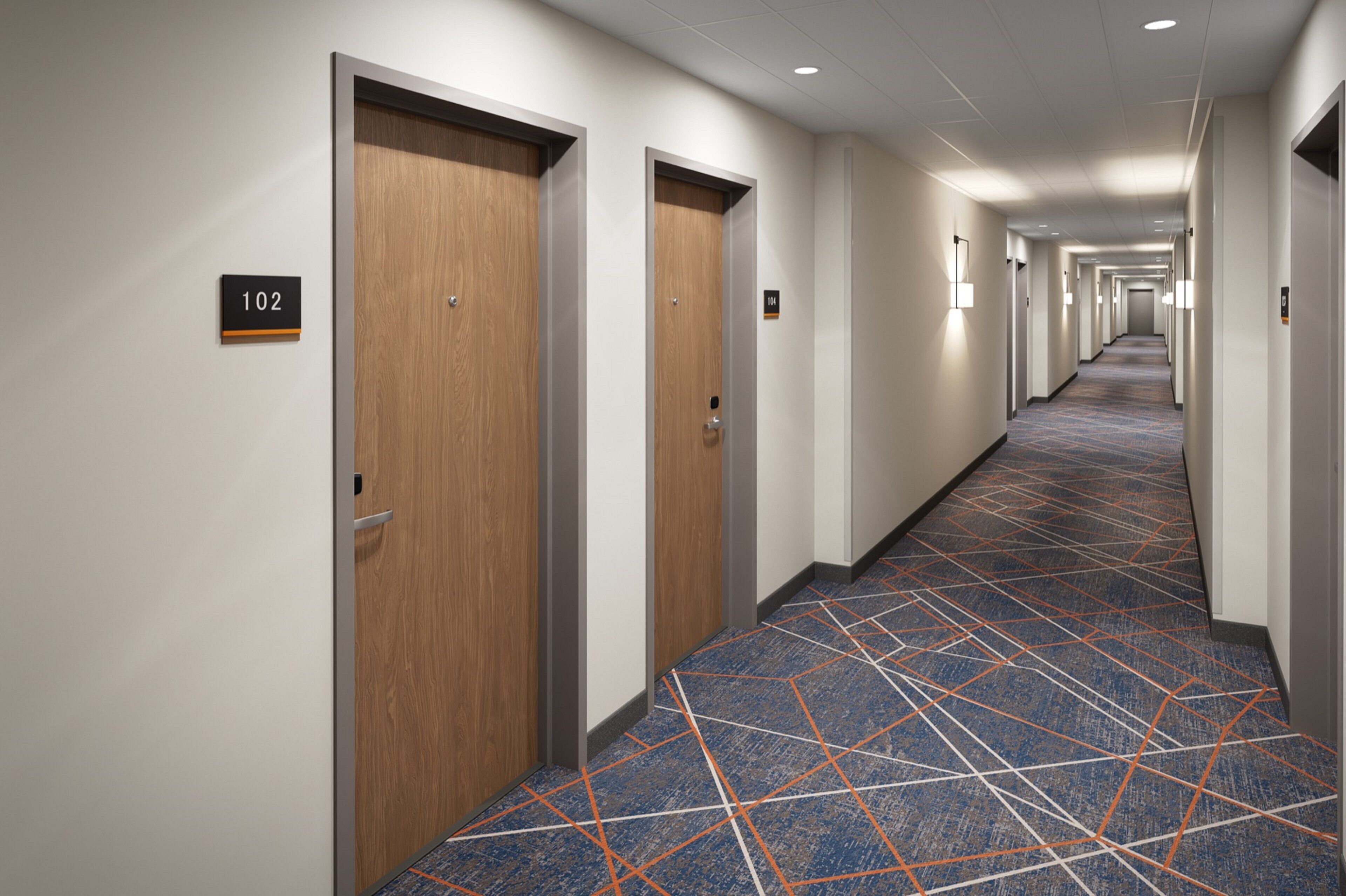 A hotel hallway with wooden doors, numbered signs, and patterned carpet.