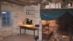 A rustic room with a stone fireplace, a wooden desk with a lamp, and bookshelves. - A cocoon in nature (Meyrignac-l'Église)