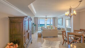 Un salón amplio con un sofá grande, una mesa de comedor con sillas y vista al océano.