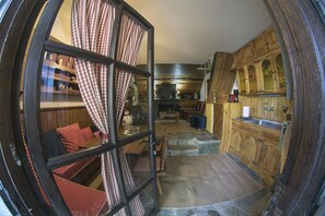 Ein gemütliches Blockhaus-Interieur mit Essbereich, Küche und einem Fenster mit karierten Vorhängen.
