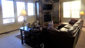 Una sala de estar con chimenea de piedra, un sofá, una mesa de centro con objetos decorativos y dos lámparas.