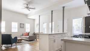 Une cuisine moderne avec des meubles blancs, un îlot central et une cuisinière intégrée.