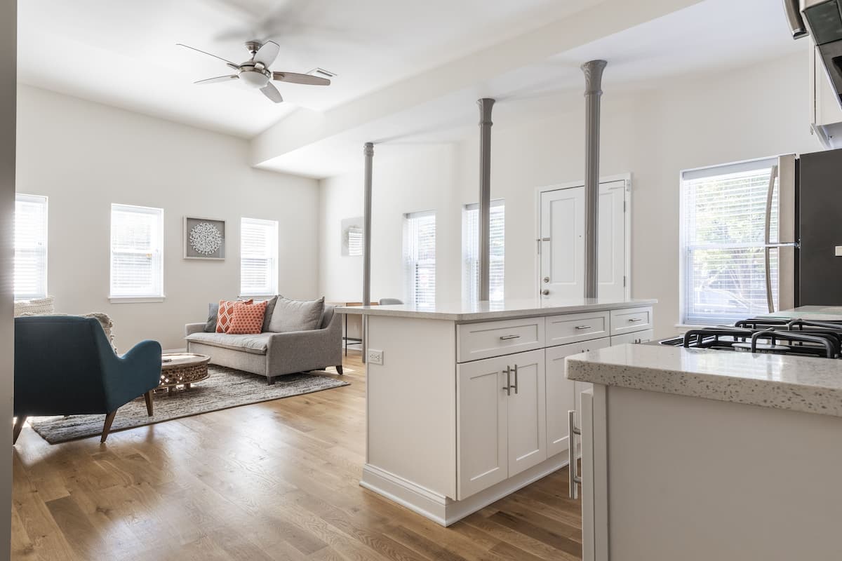 A modern kitchen with white cabinetry, a central island, and a built-in stove.