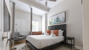 Une chambre à coucher moderne avec un grand lit, une table de chevet, une chaise et un tableau au mur.