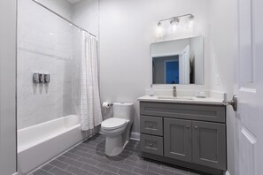 A modern bathroom with a walk-in shower, toilet, and vanity with a mirror and light fixtures. - Deedee's Mansion on Wayne (Jersey City)