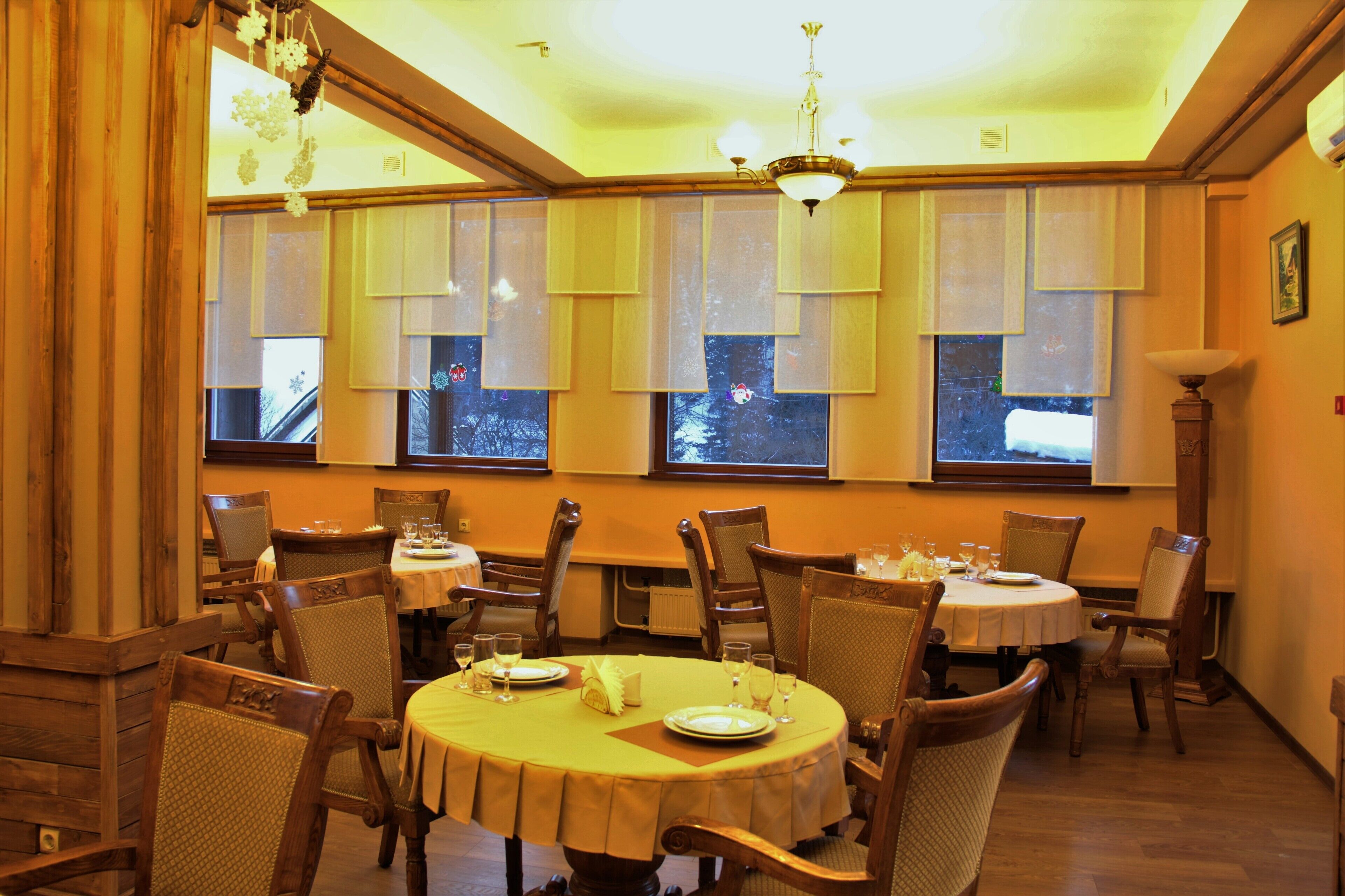 A dining area with round tables, chairs, and a chandelier.