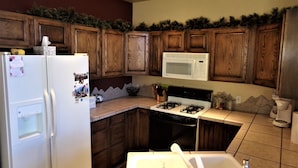 Una cocina con armarios de madera, un refrigerador blanco, un microondas, una estufa y un lavamanos.