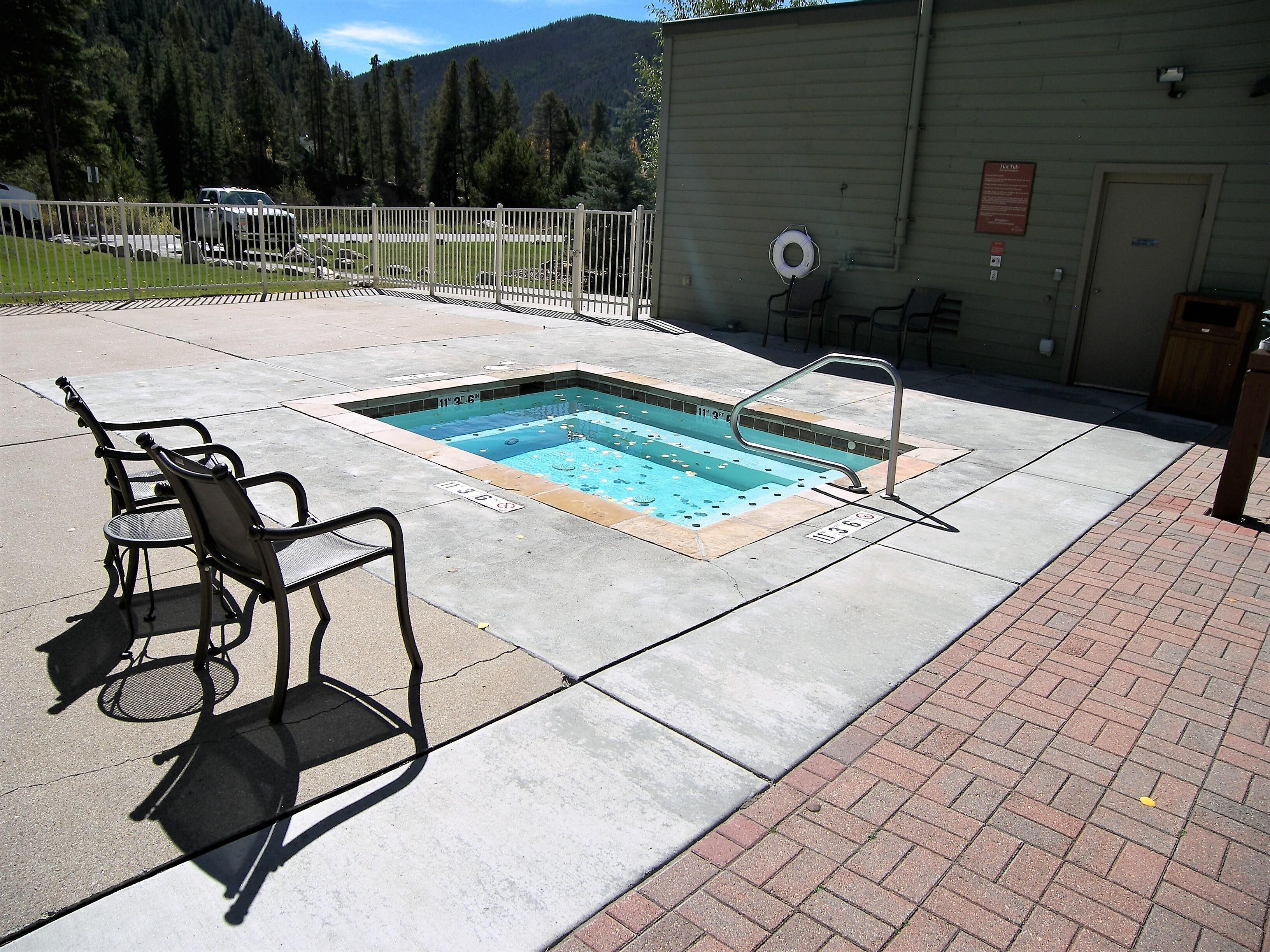 A swimming pool with a diving board, a lounge chair, and a small deck area.