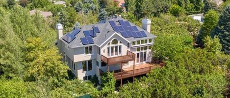 A two-story house with a large deck and solar panels on the roof.
