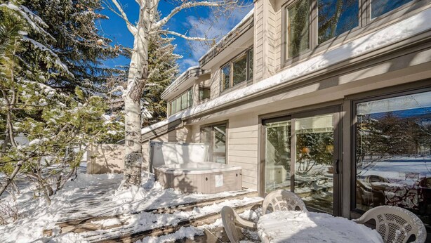 A modern house with a covered patio, outdoor seating, and a snow-covered landscape.