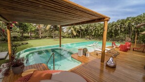 A wooden deck with a pool, lounge chairs, and a covered area. - Spectacular Luxury Mansion on the Beach. (Mata de São João)