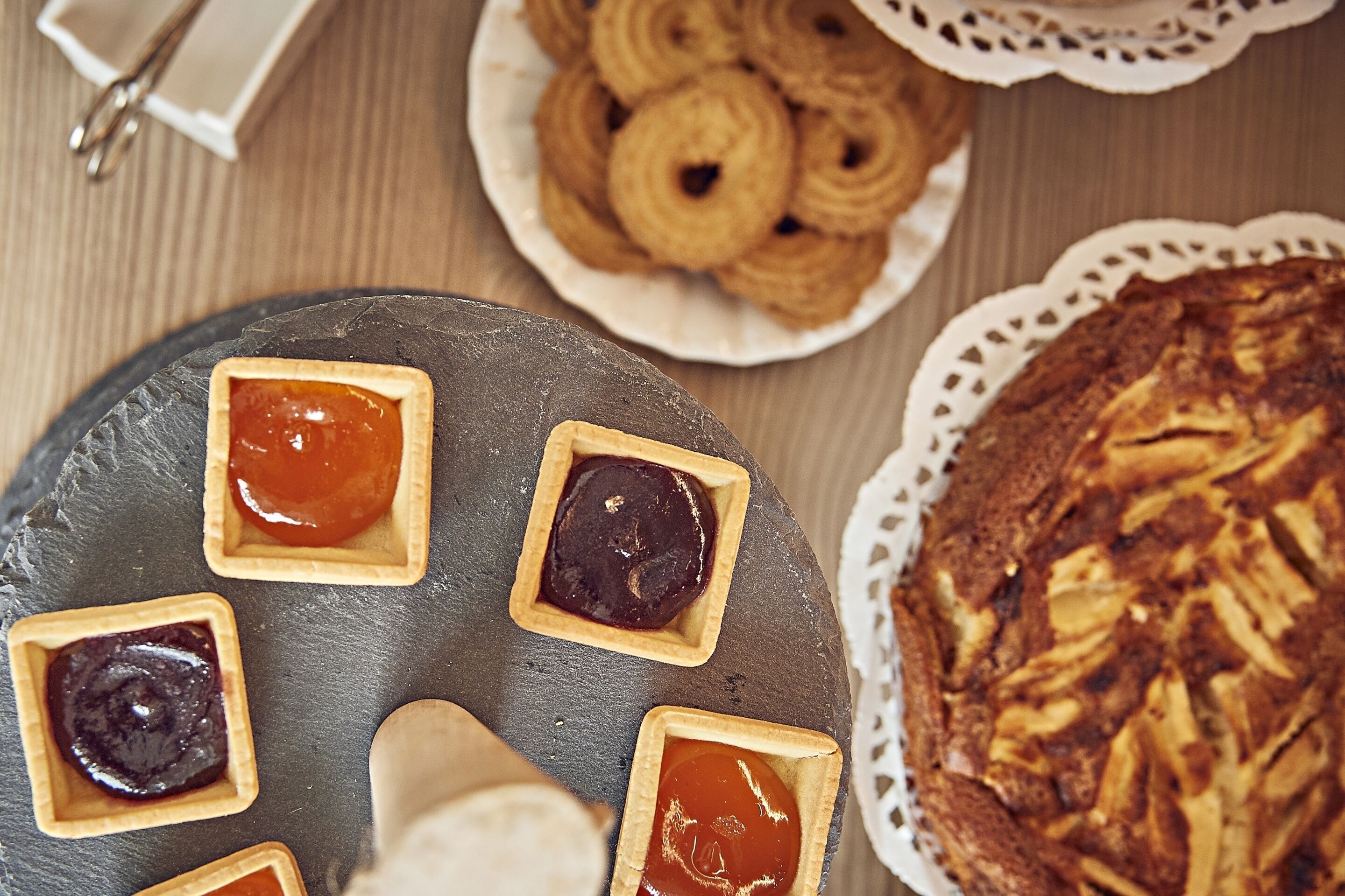 Una bandeja de postres con varios tartas y un pastel grande sobre una tabla de pizarra.