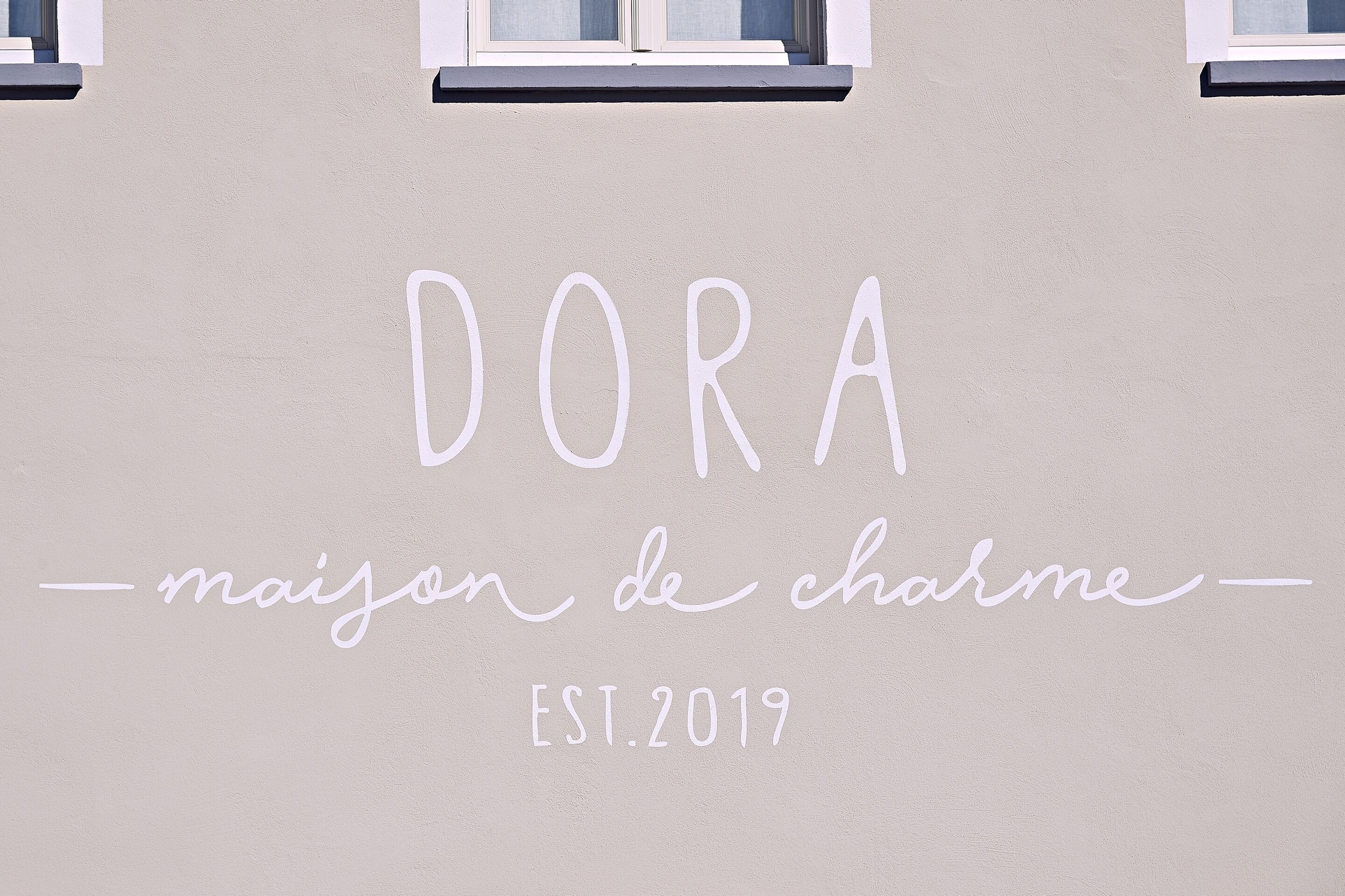 Una pared con el texto "DORA - maison de charme - EST. 2019".