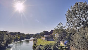 A river with a bridge, a house on a hill, and a clear sky.