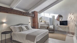 A modern bedroom with a large bed, a desk with a TV, and a chair. - Dora maison de charme (Ivrea)