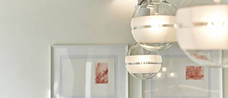 A modern chandelier with multiple spherical lights and a white wall with framed artwork.