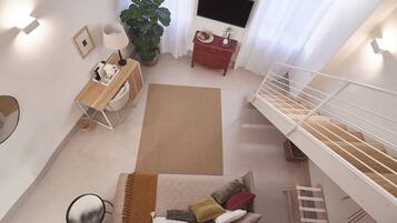 Una sala de estar moderna con un sofá, una mesa de centro, una planta grande, un televisor y una escalera.