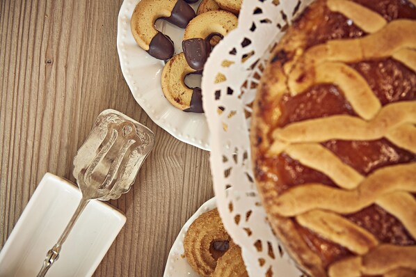 A wooden table with a plate of cookies and a pie. - Dora maison de charme (Ivrea)