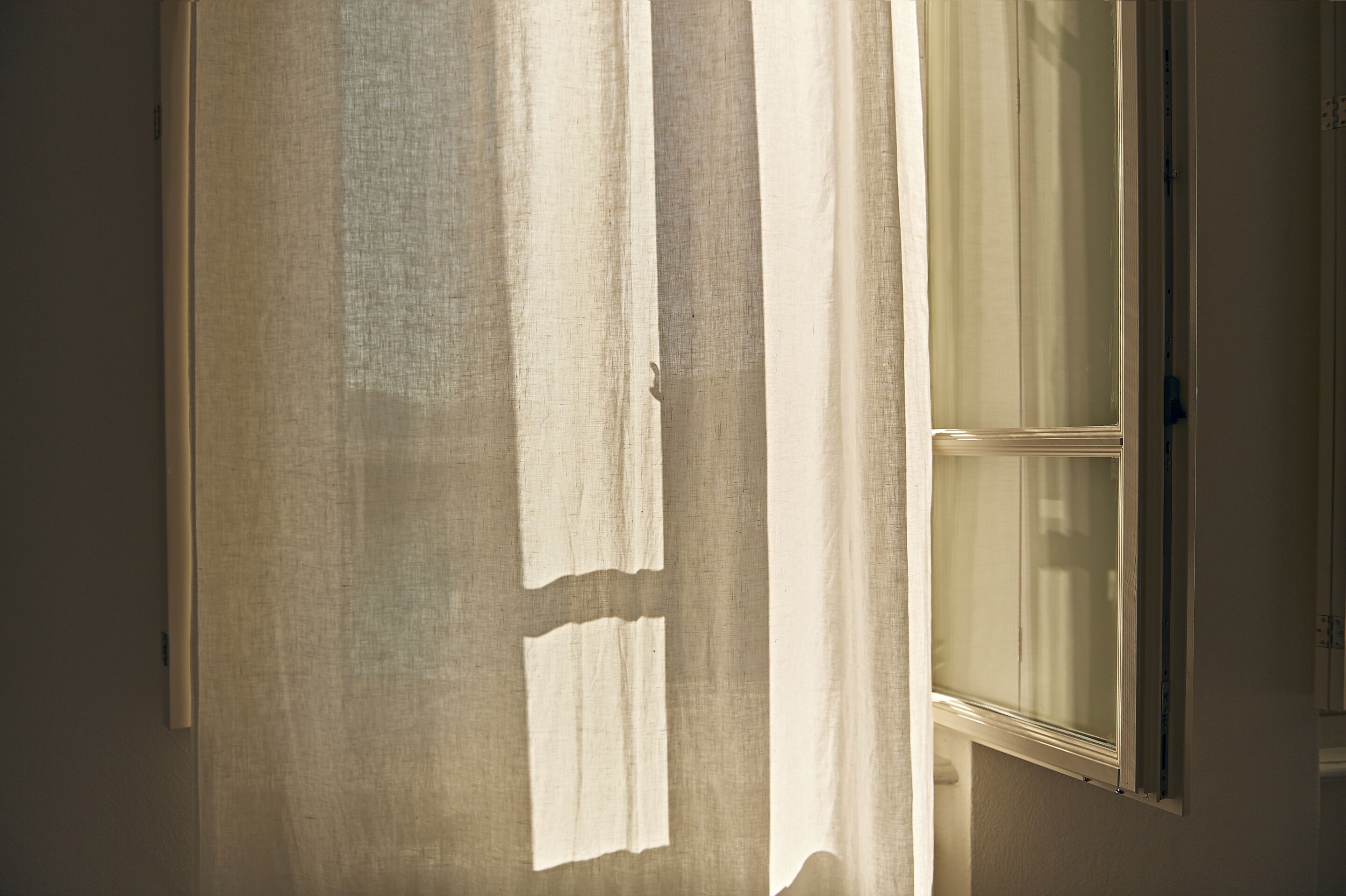 A room with a large window, a door, and a wall with a textured surface.