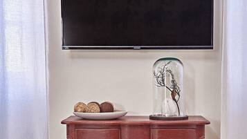 Une commode en bois avec des tiroirs, un vase en verre orné de branches et une assiette décorative.