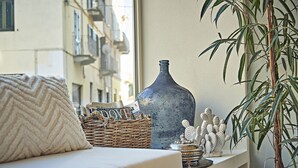 A cozy seating area with a cushioned bench, a wicker basket, a decorative vase, and a potted plant. - Dora maison de charme (Ivrea)
