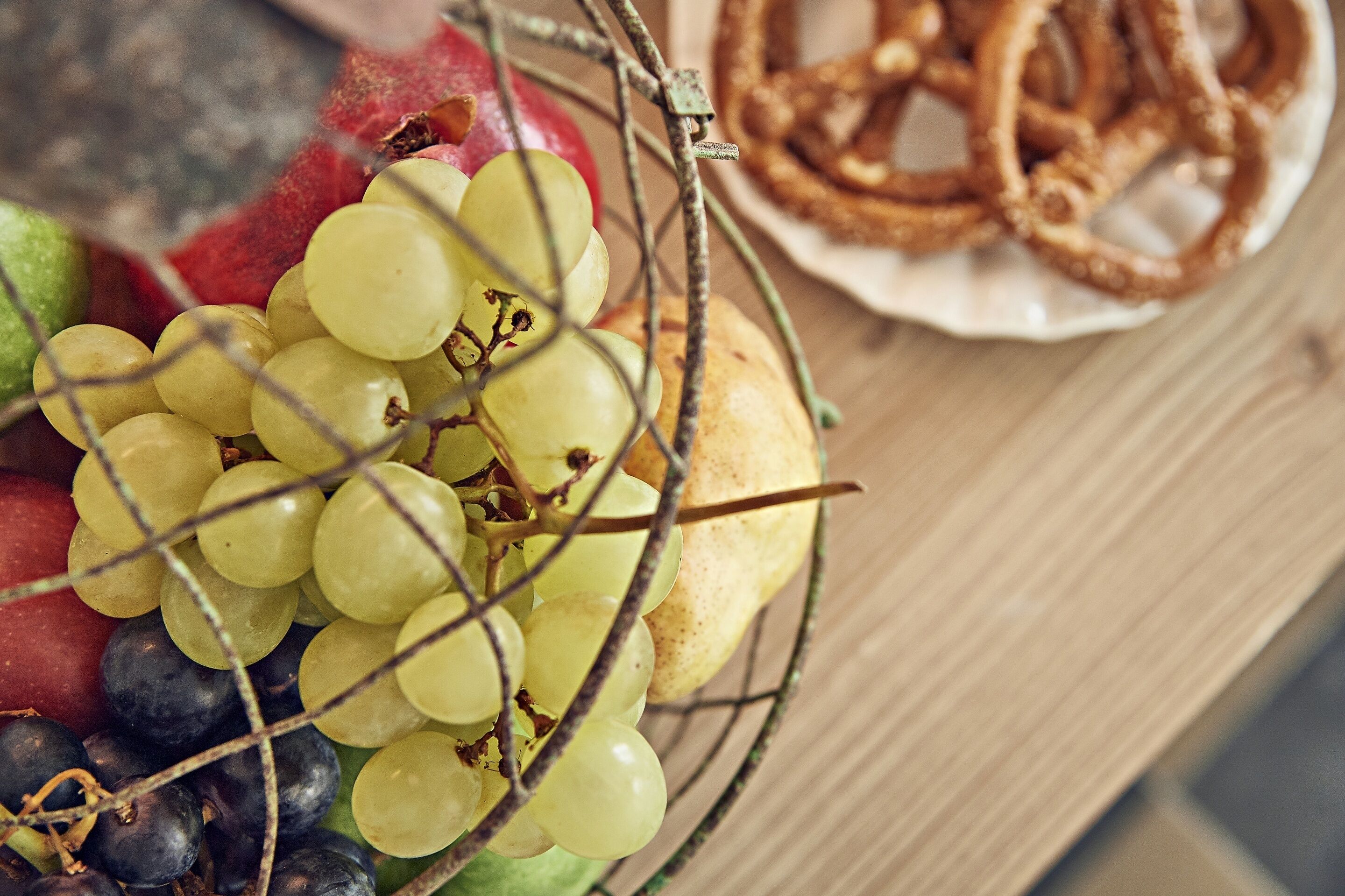 Un panier de fruits comprenant des raisins et des pommes, ainsi qu’une assiette de rondelles d’oignon frites.