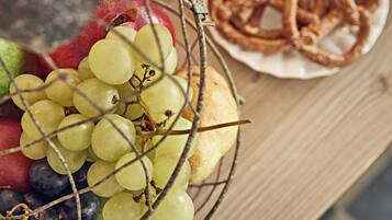 Un panier de fruits comprenant des raisins et des pommes, ainsi qu’une assiette de rondelles d’oignon frites.
