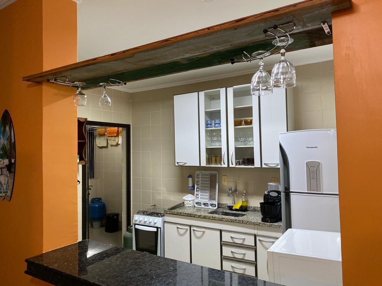 A kitchen with white cabinets, a gas stove, a refrigerator, and a coffee maker.