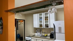 A kitchen with white cabinets, a gas stove, a refrigerator, and a coffee maker. - Apartment in Praia Grande 100 m from the beach (Ubatuba)