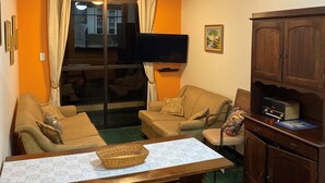 A cozy living room with a sofa set, a television, and a cabinet. - Apartment in Praia Grande 100 m from the beach (Ubatuba)