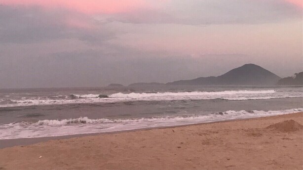 A beach with waves and a mountain in the distance. - Apartment in Praia Grande 100 m from the beach (Ubatuba)