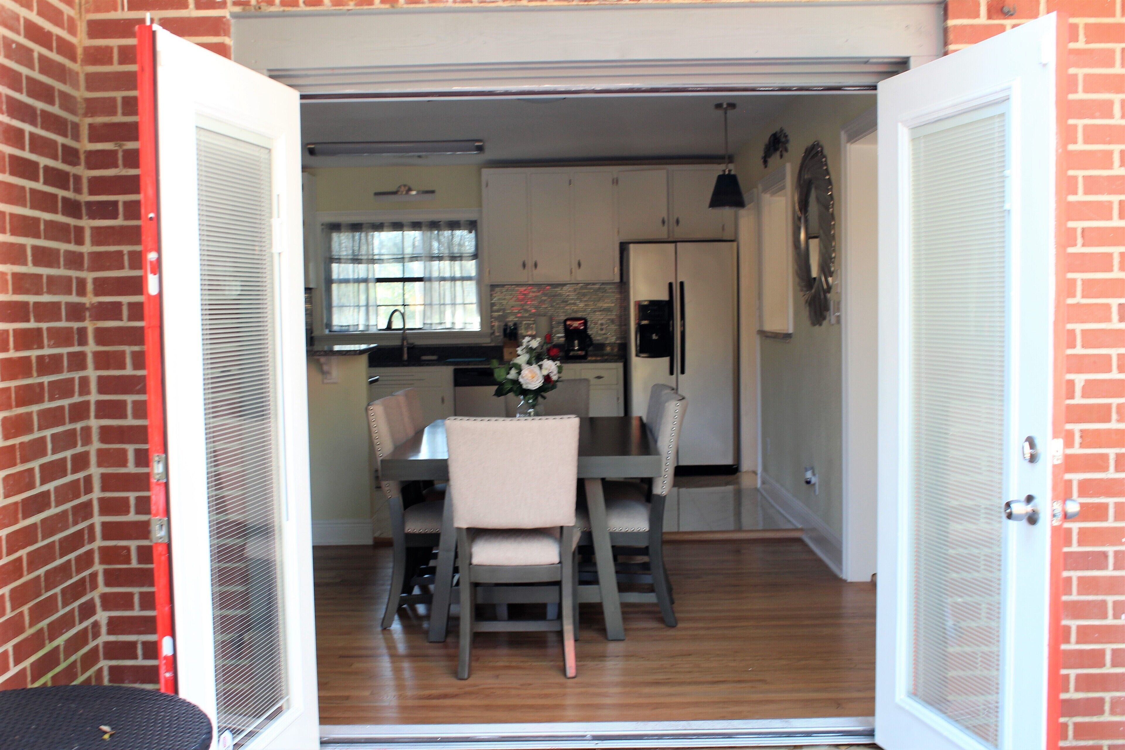 An open garage leading to a kitchen with a dining table, chairs, and a refrigerator.