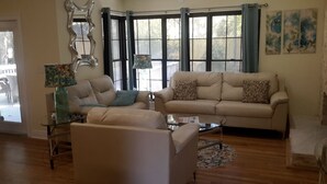 A living room with a beige sofa, a glass coffee table, and a peacock-patterned vase. - COOL HAVEN- A Quiet, Elegant, Contemporary, Incognito Retreat near FAMU/FSU (Tallahassee)