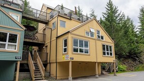 A multi-story building with a staircase leading to an upper level, a garage, and a parking area.