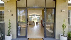 A modern house with a large glass door entrance, a covered patio area, and a well-maintained garden. - Belle Bois, Capertee Valley (Bogee)
