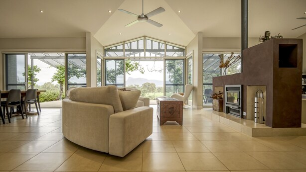 A spacious living room with a large window, a fireplace, and a ceiling fan. - Belle Bois, Capertee Valley (Bogee)