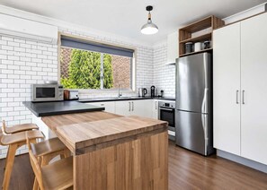 A modern kitchen with a wooden island, stainless steel appliances, and white cabinetry.