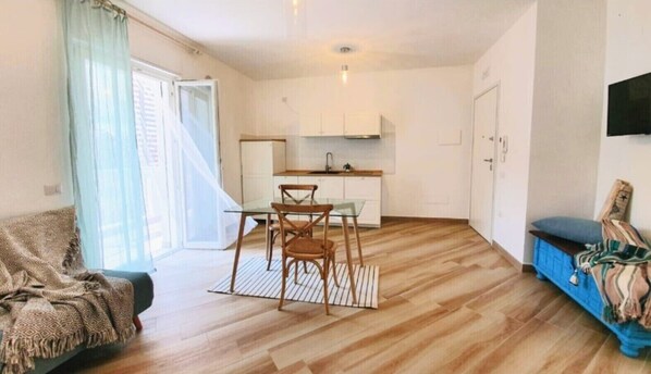 Una sala de estar moderna con comedor, cocina y un ventanal con cortinas.