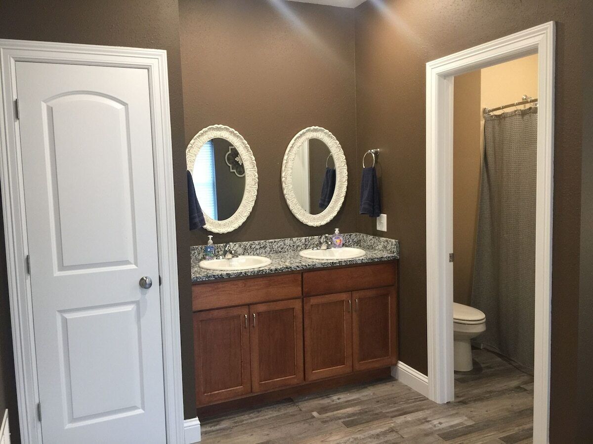 A bathroom with two sinks, wooden cabinets, and a shower curtain.
