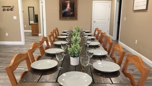Une salle à manger avec une longue table en bois, dressée pour six personnes, entourée de chaises en bois.