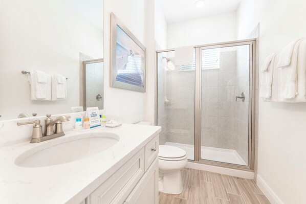 A modern bathroom with a large sink, toilet, and glass-enclosed shower.