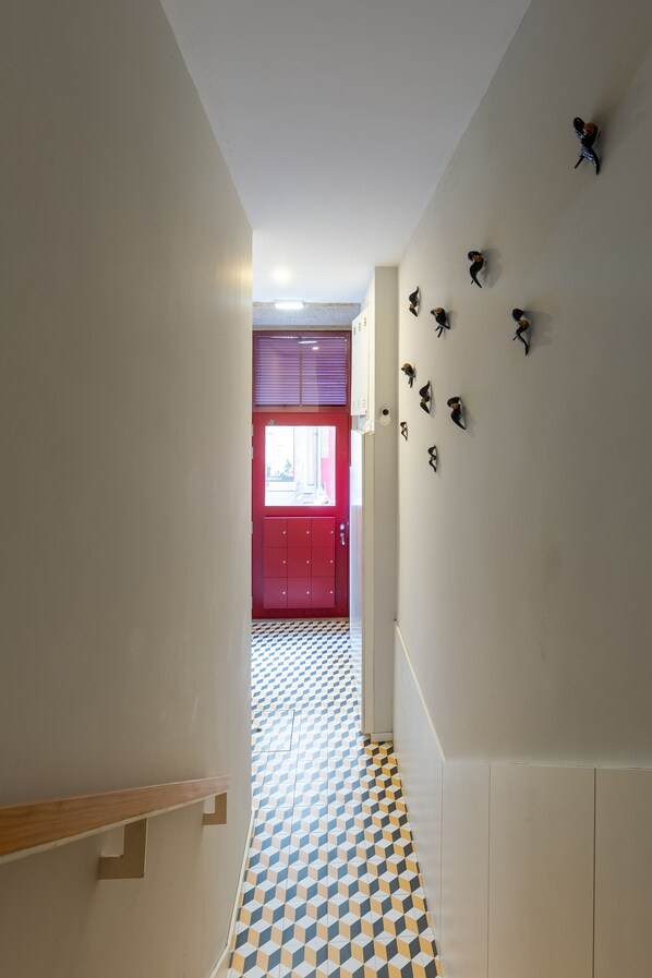 A hallway with a checkered floor, a red door, and wall-mounted bird decorations.