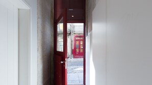 A narrow hallway with a red door leading to a cobblestone street. - Porto Belomonte Studios (Porto)