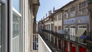 A narrow street with buildings on both sides, featuring balconies and a pedestrian walkway. - Porto Belomonte Studios (Porto)