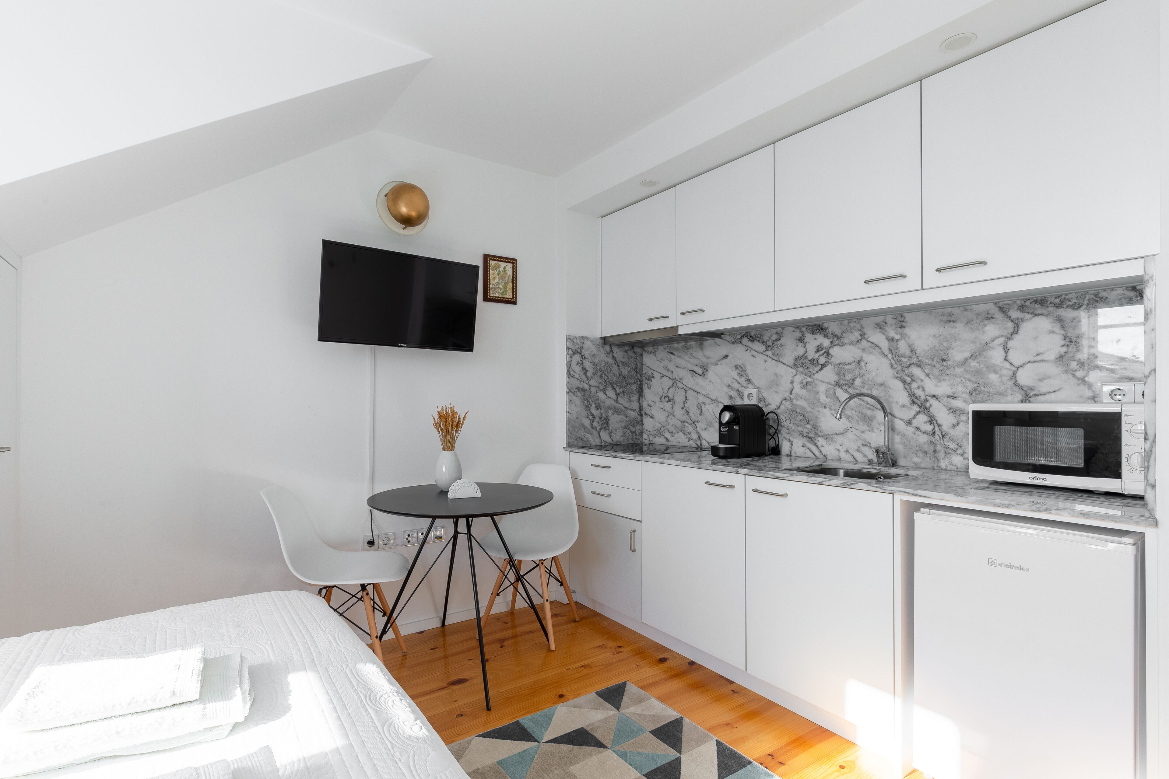 A modern kitchen with white cabinets, a marble countertop, and a built-in microwave.