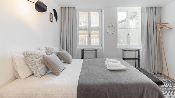 A modern bedroom with a bed, bedside tables, a hanging light, and a view of the outside. - Porto Belomonte Studios (Porto)